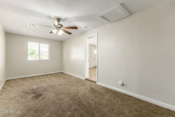 an empty room with windows and fan
