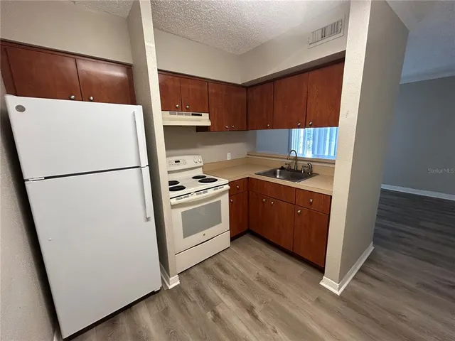 a kitchen with a refrigerator a stove top oven a sink and dishwasher with wooden floor