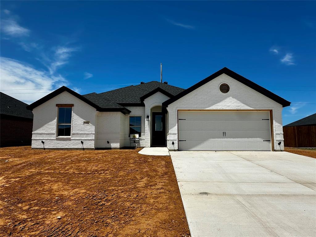 View of front facade featuring brick siding, concrete driveway, an attached garage, and a shingled roof
