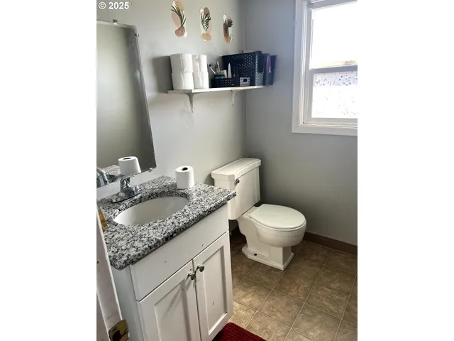a bathroom with a granite countertop toilet a sink and a window
