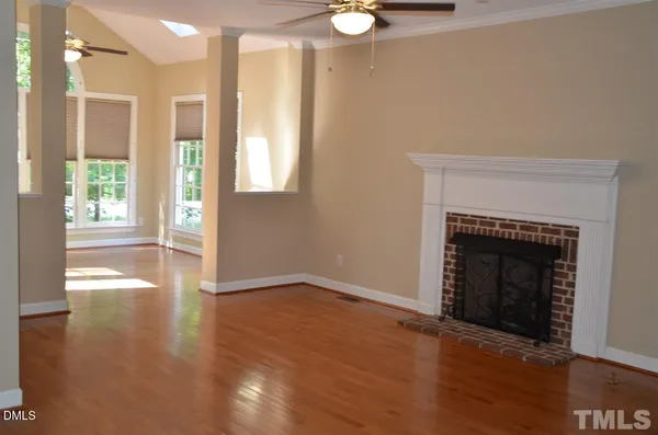 a view of an empty room with wooden floor and a fireplace