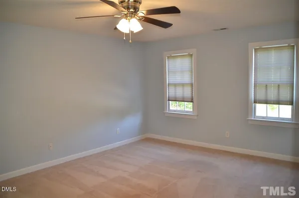 an empty room with windows and fan