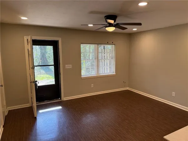a view of an empty room with wooden floor and a window
