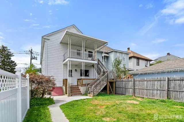 a view of a house with a small yard and a large tree