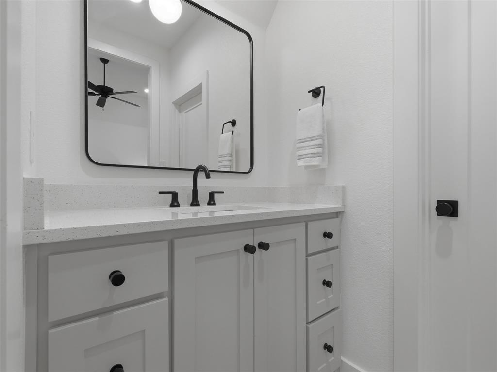 4211 Azalea Way Midlothian, TX 76065 - Photo 33 of 39 White vanity with shaker-style cabinetry, black hardware, and an integrated sink beneath a quartz countertop