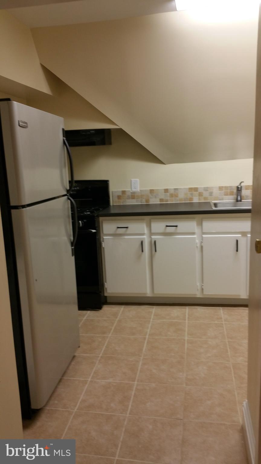 5017 Roland Avenue Baltimore, MD 21210 - Photo 21 of 35 a utility room with granite countertop cabinets and a refrigerator