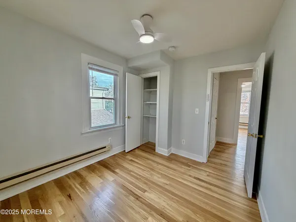 a view of empty room with wooden floor and fan