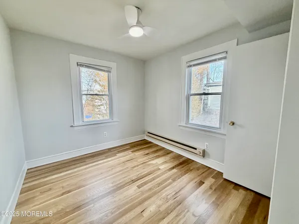 a view of empty room with wooden floor and fan