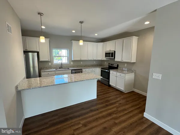 a kitchen with kitchen island a sink a stove a refrigerator and white cabinets