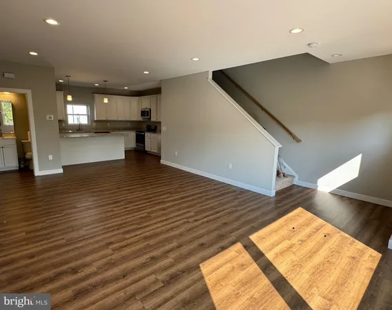 a view of an empty room with wooden floor and a hallway