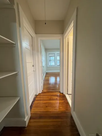 a view of a hallway with wooden floor and a window