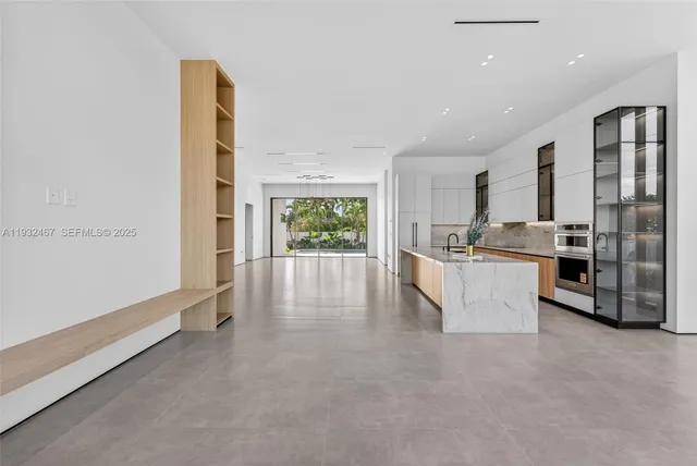 a large white kitchen with a refrigerator a stove a sink and a large window