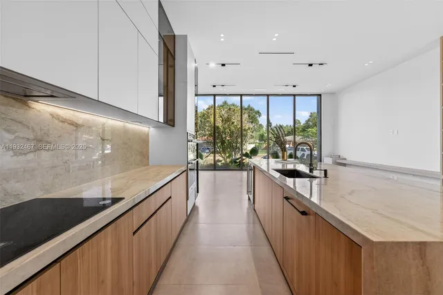 a view of a kitchen with stainless steel appliances granite countertop a sink and a large window