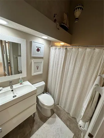 a bathroom with a sink a toilet and shower curtain