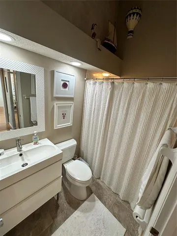 a bathroom with a sink a toilet and shower curtain