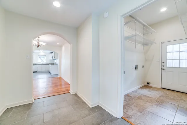 an empty room with windows and chandelier fan