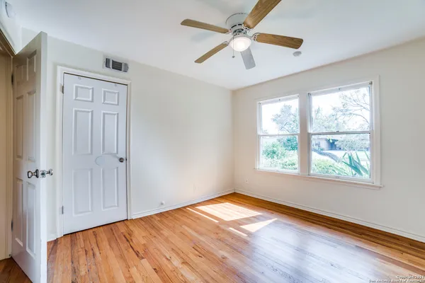 a view of empty room with wooden floor and fan