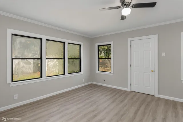 an empty room with wooden floor fan and windows