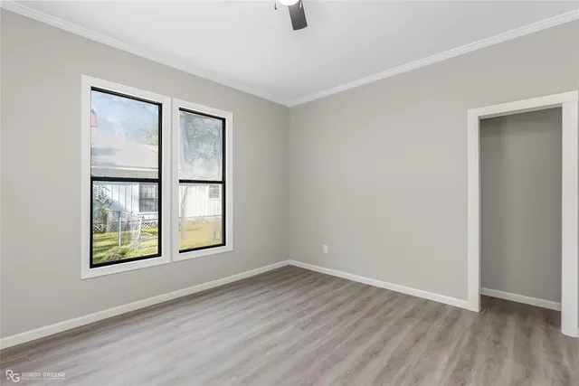 an empty room with wooden floor and windows