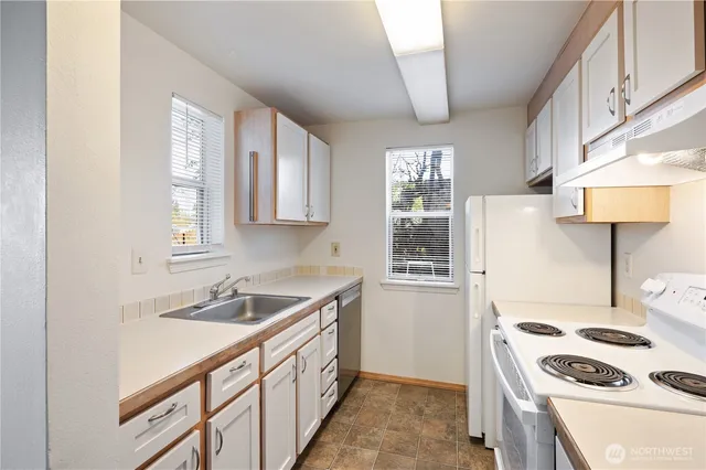 a kitchen that has a sink a stove and a refrigerator