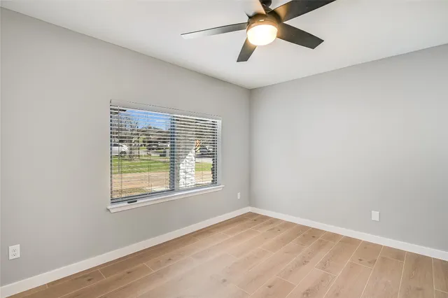 an empty room with a window and a fan