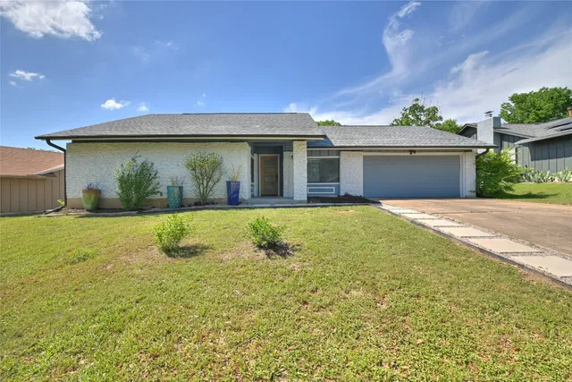 a view of a house with a yard and potted plants