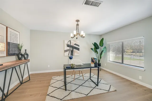 a dining room with chandelier fan and wooden floor