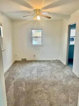 an empty room with a window and a ceiling fan