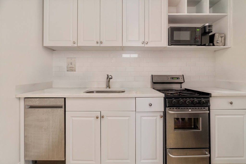 a kitchen with white cabinets and stainless steel appliances