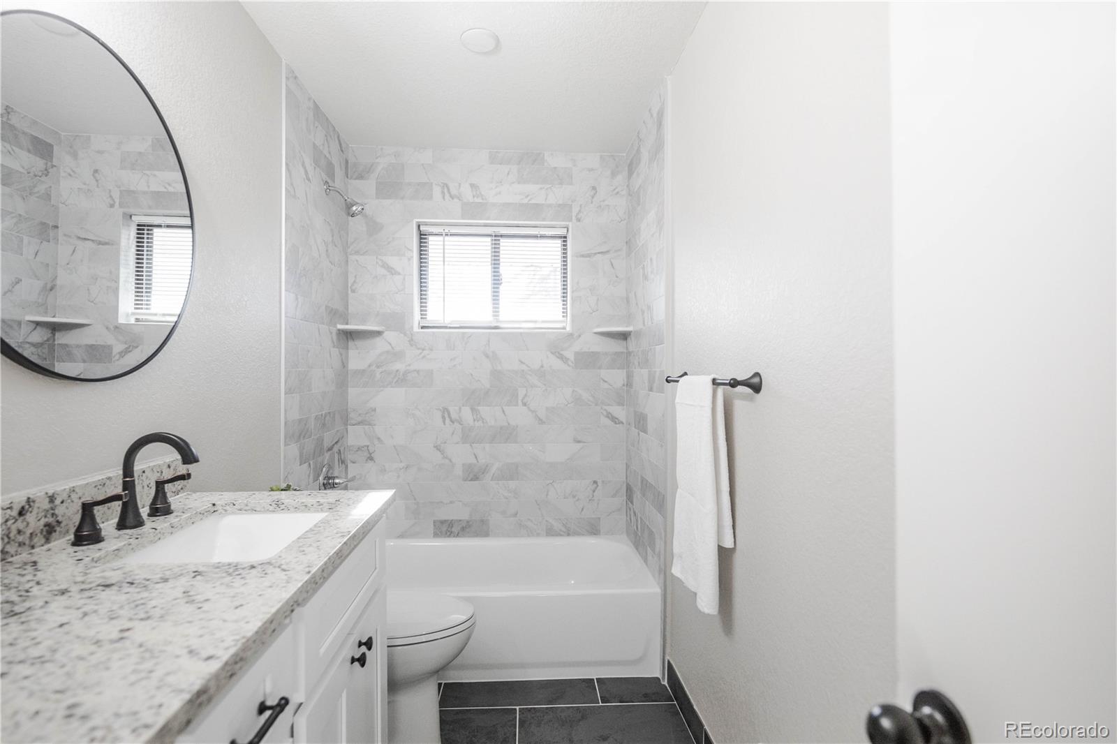 820 Drake Street Denver, CO 80221 - Photo 17 of 48 a bathroom with a granite countertop sink a mirror and a bathtub