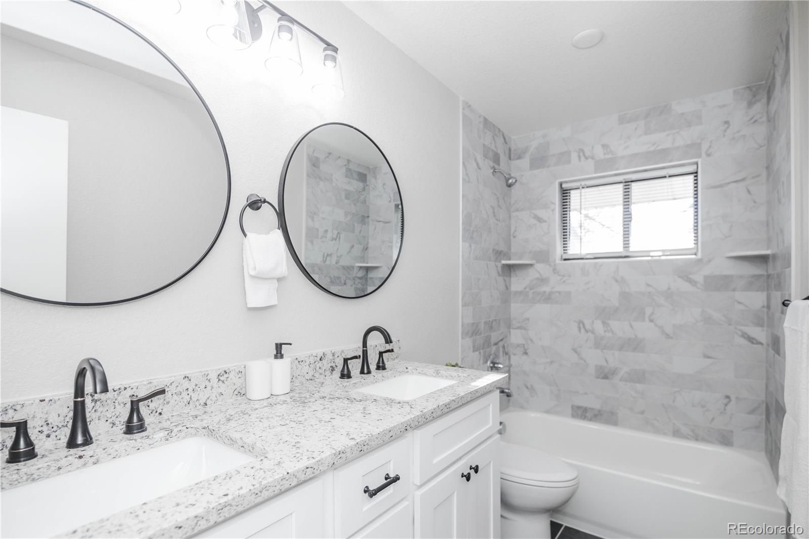 820 Drake Street Denver, CO 80221 - Photo 18 of 48 a bathroom with a granite countertop toilet a sink a mirror and bathtub