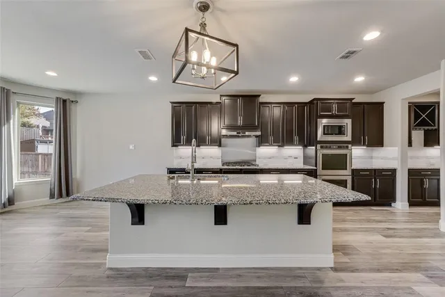 a large kitchen with stainless steel appliances kitchen island a large counter top and wooden floors