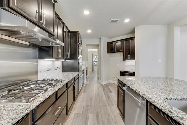 a kitchen with stainless steel appliances kitchen island granite countertop a stove and a sink