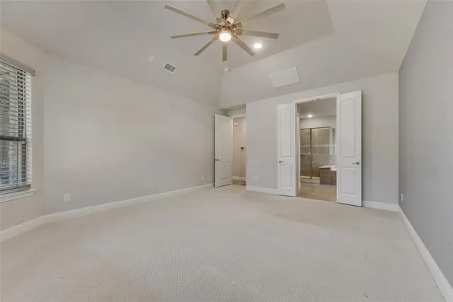 an empty room with chandelier fan and windows