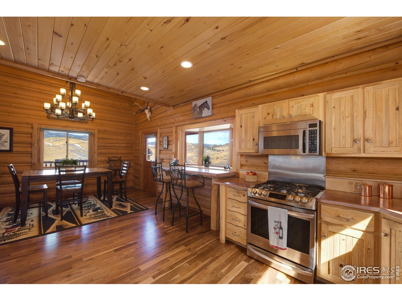370 Blue Mountain Trail Lyons, CO 80540 - Photo 13 of 37 a kitchen with stainless steel appliances granite countertop a stove top oven a dining table and chairs with wooden floor