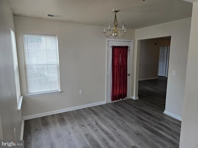 an empty room with wooden floor closet and windows