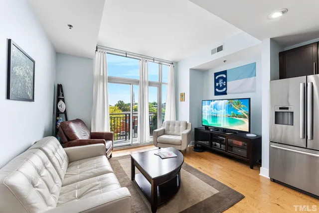 a living room with furniture flat screen tv and a refrigerator