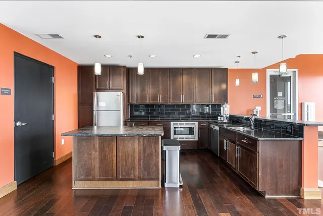 a kitchen with kitchen island granite countertop wooden floors and stainless steel appliances