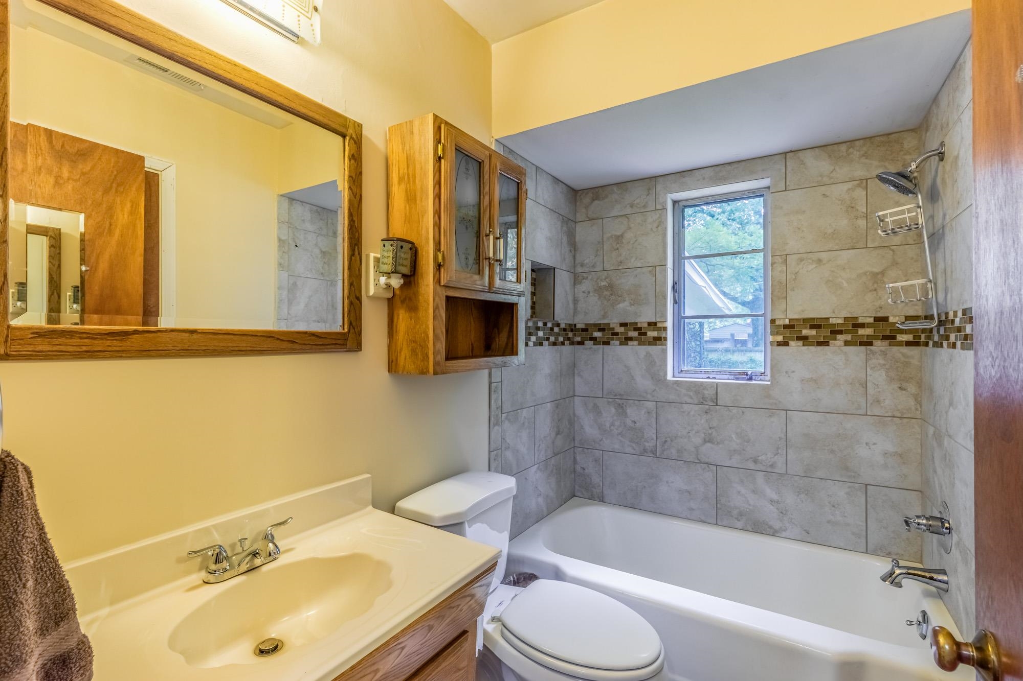 4313 Rhodes Avenue Memphis, TN 38111 - Photo 20 of 25 a bathroom with a sink mirror bathtub and toilet