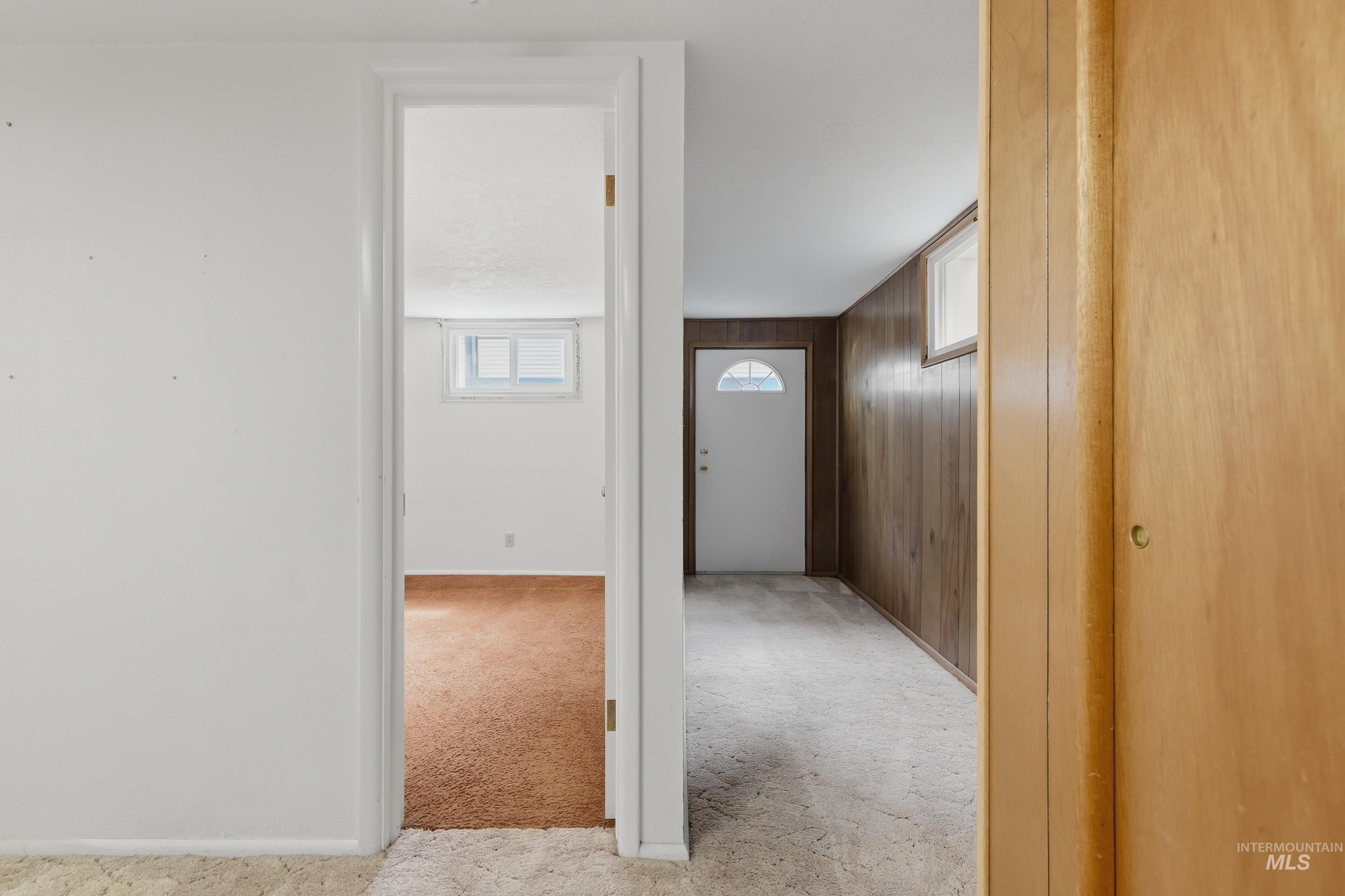 504 West Howe Street Boise, ID 83706 - Photo 37 of 47 Interior hallway with light wood paneling, white door with arched glass insert, and light-colored carpeting
