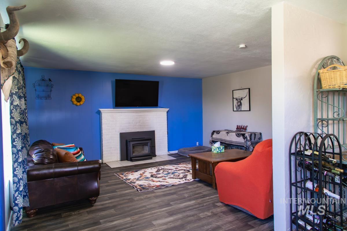 1404 Rochester Street Caldwell, ID 83605 - Photo 7 of 29 Living area featuring wood-finish flooring, a white brick-style fireplace with a dark insert, and a prominent accent wall