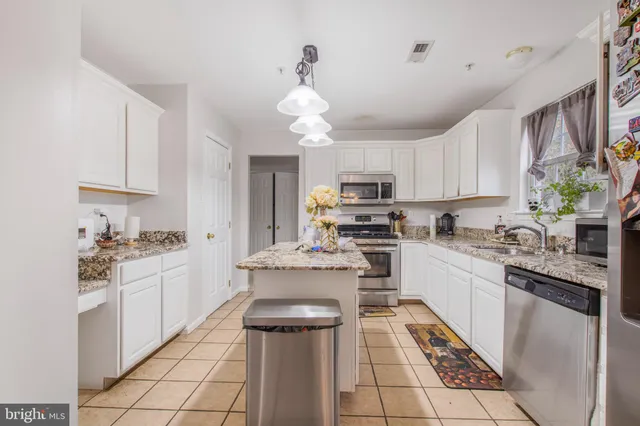 a kitchen with kitchen island granite countertop a sink counter top space appliances and cabinets
