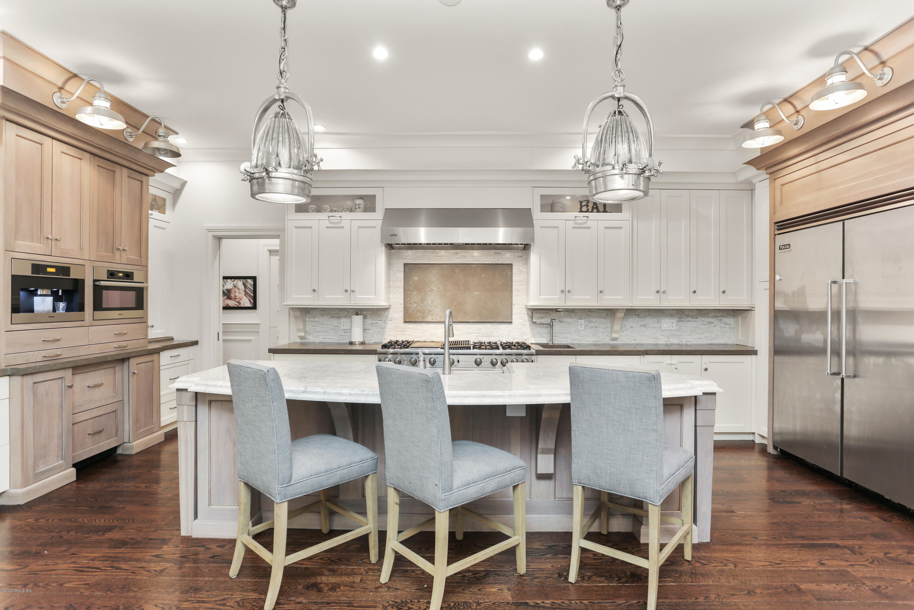 a kitchen with stainless steel appliances kitchen island granite countertop a table chairs sink and cabinets