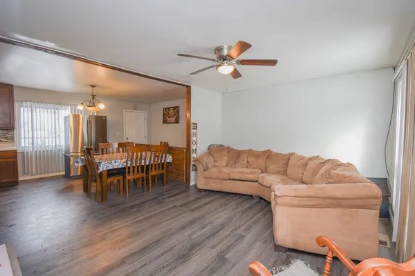 a living room with furniture and a dining table with wooden floor
