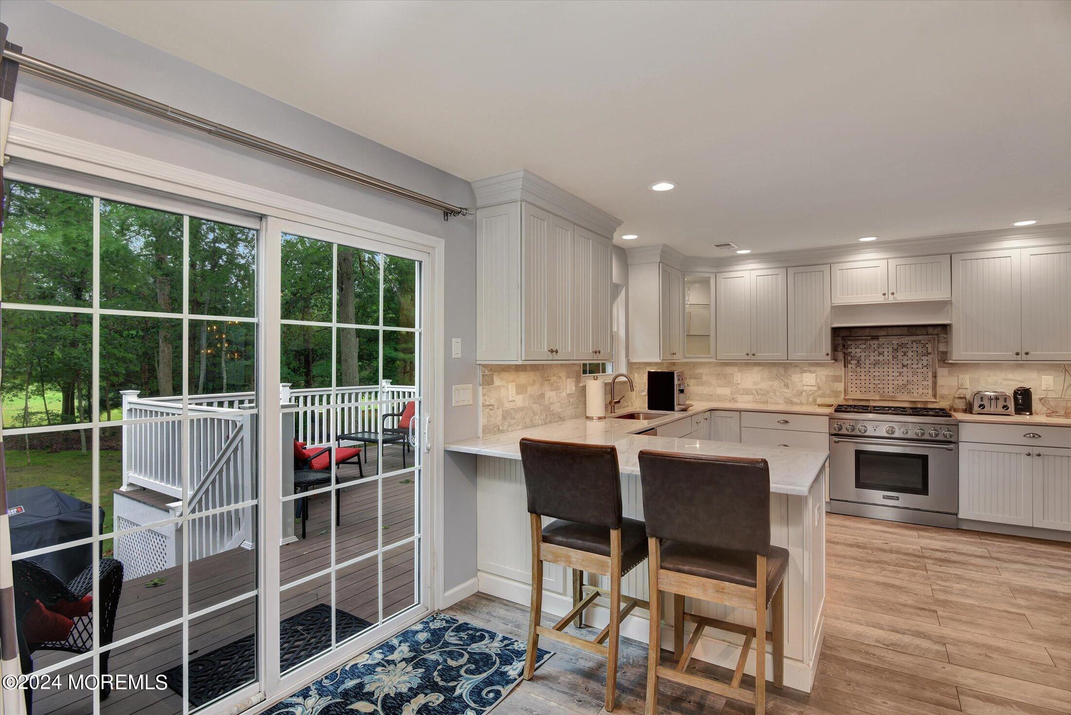 29 Nate Lane Howell, NJ 07731 - Photo 13 of 42 a kitchen with stainless steel appliances kitchen island granite countertop a stove a sink a dining table and chair with wooden floor