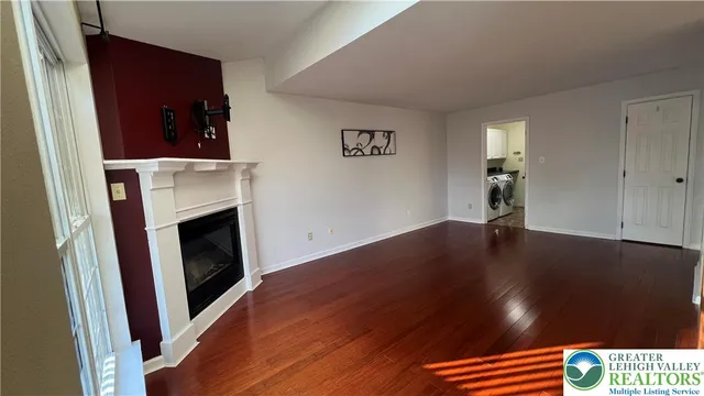 a view of an empty room with wooden floor and a fireplace
