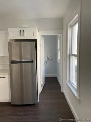 a view of a refrigerator in kitchen and an empty room