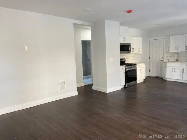 a view of cabinets stainless steel appliances wooden floor and window