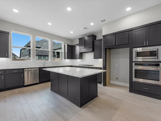a kitchen with stainless steel appliances granite countertop a stove a sink and a refrigerator