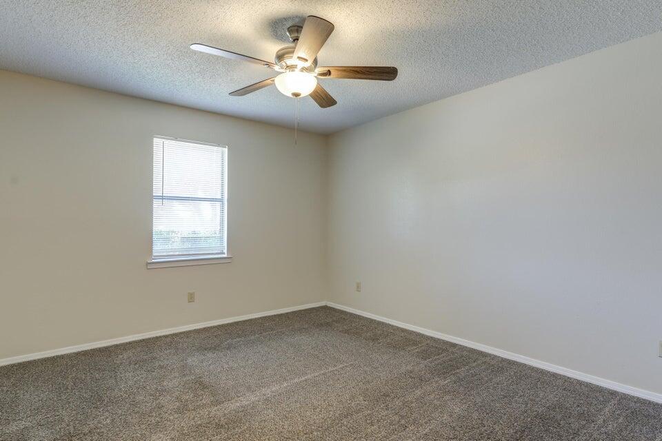 3401 101st Street Lubbock, TX 79423 - Photo 26 of 28 an empty room with a chandelier fan and windows